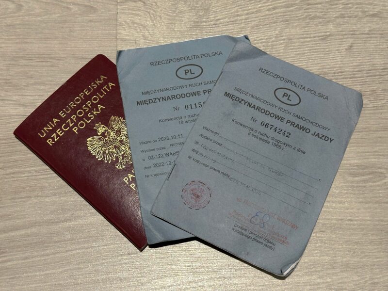 Polski paszport i dwa międzynarodowe prawa jazdy na drewnianym stole