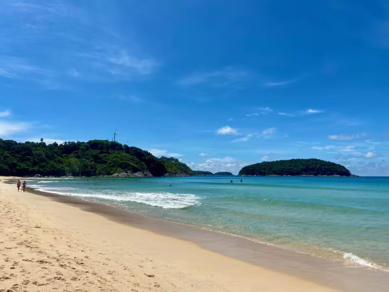 Plaża w phuket w tajlandii z turkusową wodą, żółtym piaskiem i zielonymi wzgórzami w tle