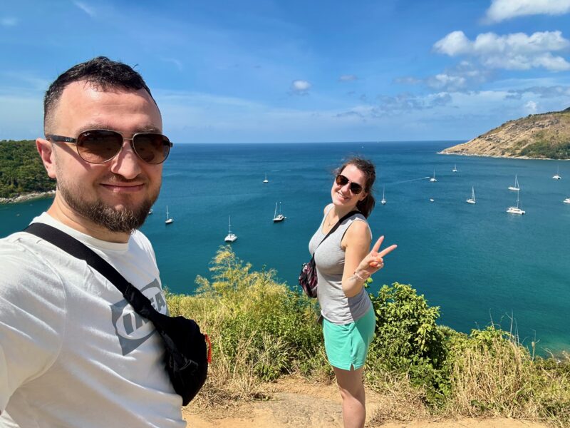 Para zakochanych robi selfie na klifie z widokiem na zatokę phuket z żaglówkami.