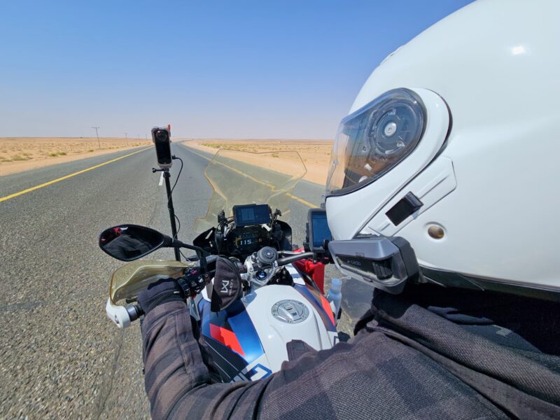 Motocyklista na pustynnej drodze w arabii saudyjskiej z kamerą na motocyklu.