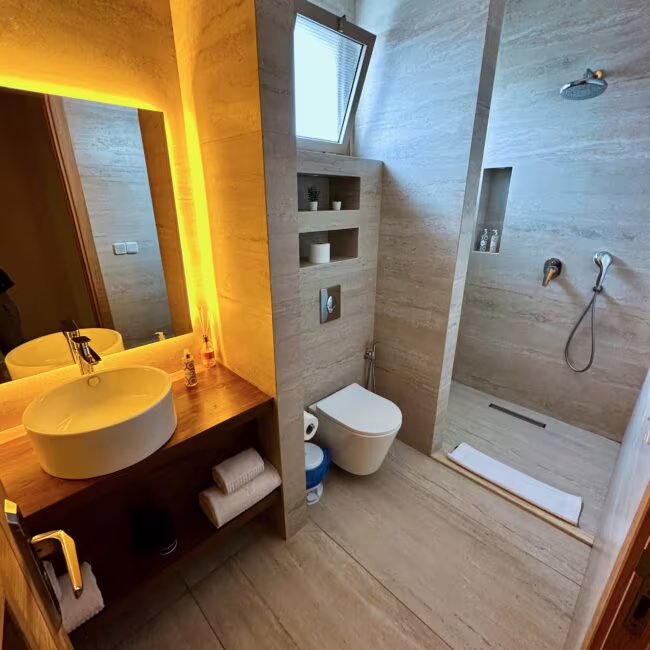 Essaouira hotel, nasz nocleg: nowoczesna łazienka z umywalką, toaletą i prysznicem, ciepłe żółte światło