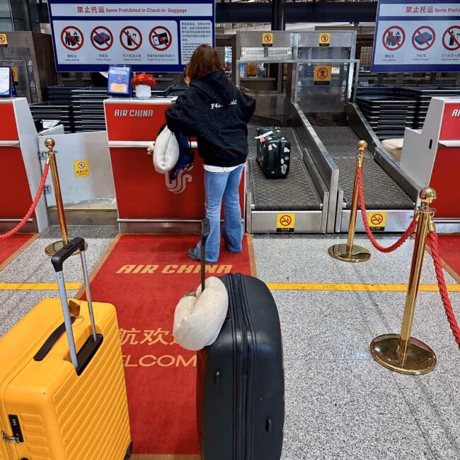 Stanowisko odprawy air china na lotnisku w pekinie, z pasażerką i walizkami przy stanowisku check-in