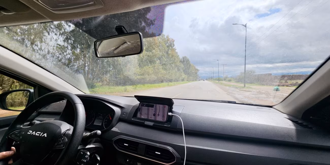 Widok z wnętrza samochodu dacia na drogę w maroku, przed maską widać prostą szosę i pochmurne niebo